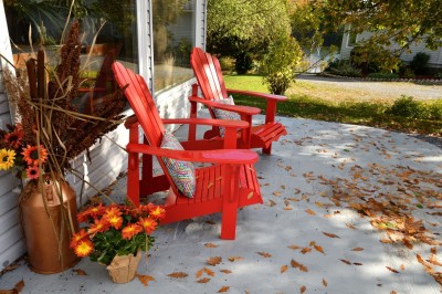 Muskoka chairs on a patio with fall decor.