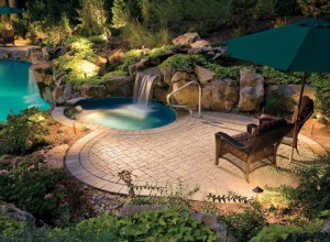 Beautiful and modern backyard landscaping design with a waterfall and inground pool.